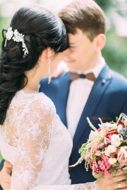 Gelin buketi tutarak ve damat ile sarılma arkadan görünüm.