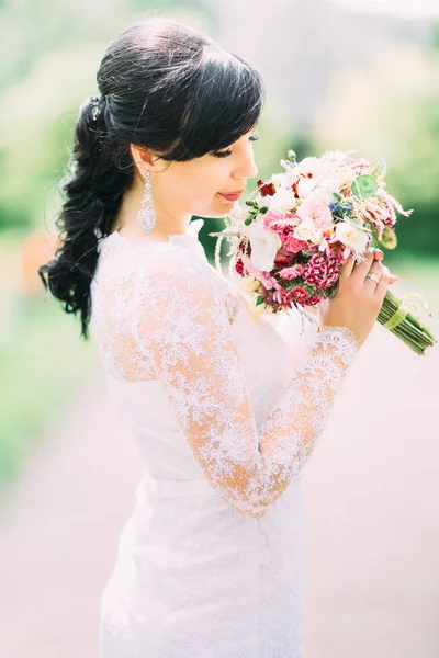 O retrato lateral da noiva cheirando o colorido buquê de casamento . — Fotografia de Stock