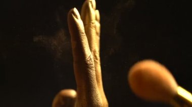 Makyaj sanatçısı onları altın siyah arka plan yapmak için Afrika parmaklar üzerinde fırça ile Bronzlaştırıcı ayırıyor. Yakın çekim görünümü. Yüzü olmayan.