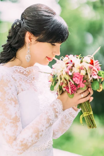 Närbild sida utomhus porträtt av den vackra bruden lukta den färgglada brudbukett. — Stockfoto