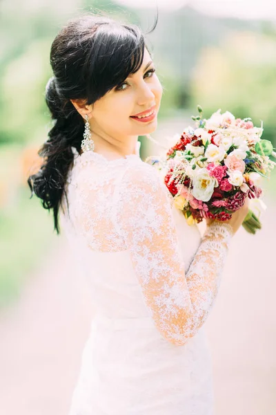 El hermoso retrato al aire libre de la novia sonriente sosteniendo el colorido ramo de bodas . — Foto de Stock