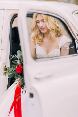 Güzel sarışın gelin beyaz eski model araba içinde. Arka plan üzerinde sonbahar orman