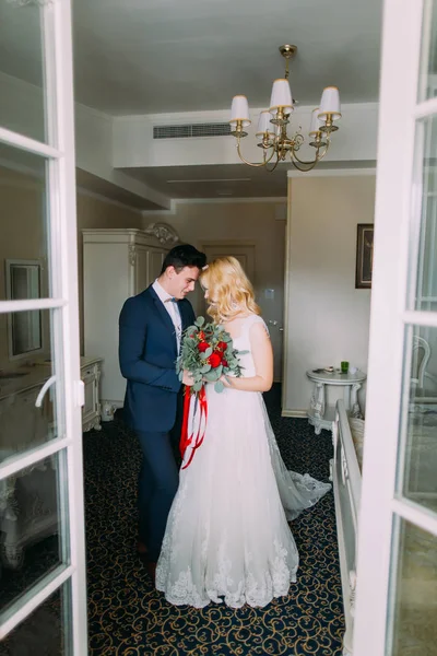 O belo par de casamento amorosamente olha um para outro. Buquê de rosas nas mãos — Fotografia de Stock