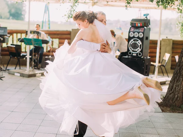The smiling groom is spinning the beautiful bride on the street. — Stock Photo, Image