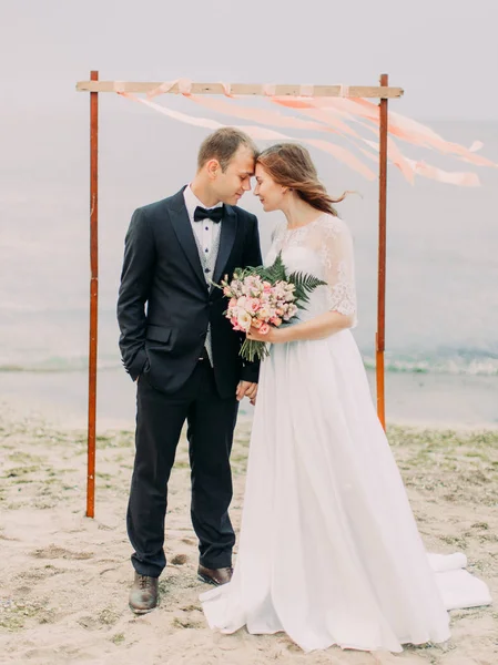 Vista completa de los recién casados de pie cabeza a cabeza en la playa . —  Fotos de Stock