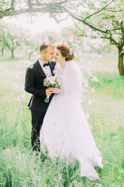 Yeni evliler kafa kafaya bahar döneminde ağaç üzerinde asılı kağıt kuğular önünde dikiliyorsun.