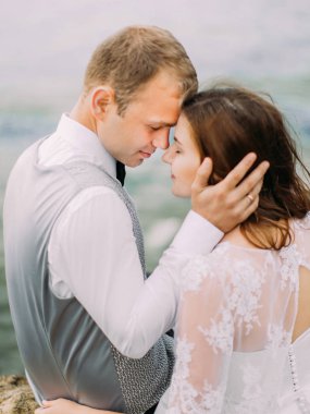 Yeni evliler deniz arka plan, yakın çekim arka portresi. Damat gelinin yüzü okşuyor.