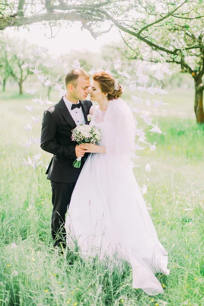 Yeni evliler kafa kafaya bahar döneminde ağaç üzerinde asılı kağıt kuğular önünde dikiliyorsun.