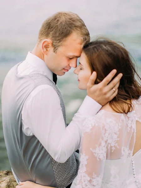 Yeni evliler deniz arka plan, yakın çekim arka portresi. Damat gelinin yüzü okşuyor.