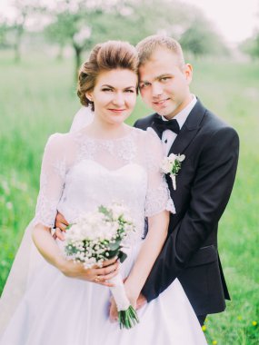 Mutlu yeni evliler portresi. Damat gelini geri sarılıyor.