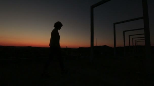 Silhouette de femme solitaire réfléchie debout sur le pont high-tech sur le coucher de soleil rouge — Video