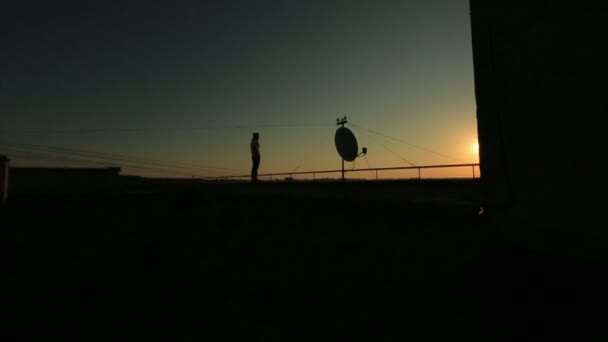 Silhouet van jonge knappe vertrouwen zakenman op het dak van de wolkenkrabber kijkt op stedelijke industriële stadsgezicht op zonsondergang — Stockvideo