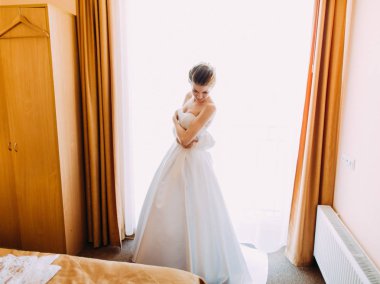 Gelin odasında uzun beyaz gelinlik içinde yatay yan görünüm.