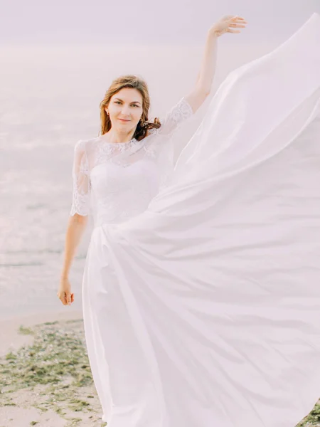 L'abito da sposa della sposa svolazza nel vento sullo sfondo del mare . — Foto Stock