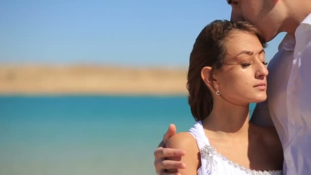 Images de mariage tendre du beau marié embrassant doucement la belle mariée dans la tête à l'arrière-plan flou de la mer en Egypte . — Video