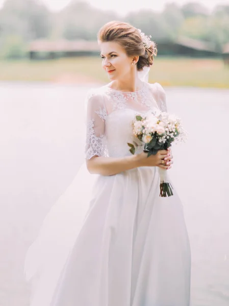 La vista laterale della sposa con il bouquet di nozze sullo sfondo del fiume . — Foto Stock