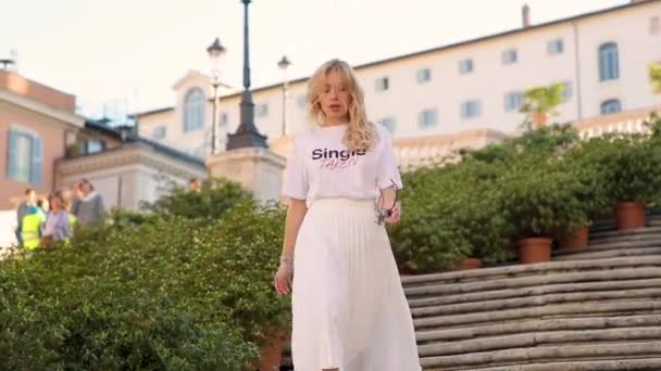 Beautiful young woman in white fashion look descends the stairs alone in the center of Rome at sunset. Day walk in the city. 4K video. — Stock Video