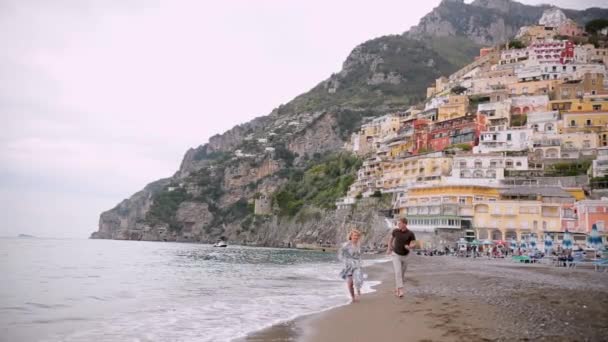 Βίντεο του ζευγαριού στην παραλία ρομαντικό κρατώντας τα χέρια τρέχει παιχνιδιάρικο. Νεαρό ερωτευμένο ζευγάρι που απολαμβάνει ρομαντισμό με casual κομψά ρούχα στις πολυτελείς διακοπές διακοπών στην παραλία. Βίντεο 4k. — Αρχείο Βίντεο