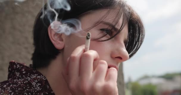 Κοντινή θέα της νεαρής όμορφης μελαχρινής γυναίκας που καπνίζει στο σπίτι. 4k, αργή κίνηση. — Αρχείο Βίντεο