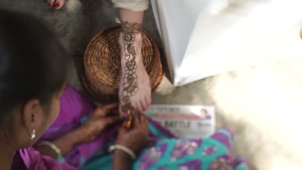 The indian woman artist is doing the henna tattoo on the female leg. Mehendi concept. Top view. — Stockvideo