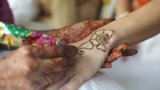 Female hands of the indian artist doing the mehending using the paste of henna on the female hands. No face. Close-up view. — Stockvideo