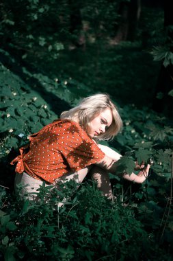 Koyu yeşil bitkilerin arasında oturan güzel bir kadın, dışarıda dinlenen güzel bir kız..