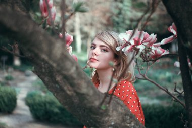 Sakura dallarının arasında duran güzel bir kadın, dışarıda dinlenen güzel bir kız. Yumuşak pembe renkler