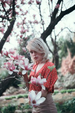 Sakura dallarının arasında duran güzel bir kadın, dışarıda dinlenen güzel bir kız. Yumuşak pembe renkler