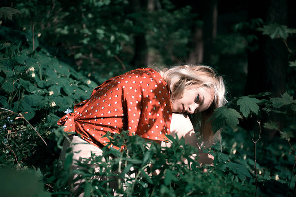 Красивая женщина сидит среди темно-зеленых растений, красивая девушка расслабляется на открытом воздухе
.