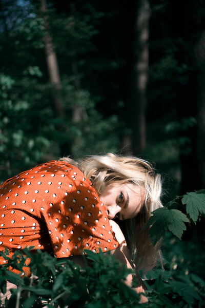 Красивая женщина сидит среди темно-зеленых растений, красивая девушка расслабляется на открытом воздухе. Крупный план
