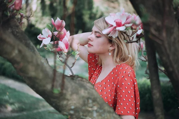 Mulher bonita em pé entre ramos sakura, menina bonita relaxante ao ar livre. Cores rosa suave — Fotografia de Stock