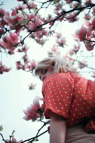 Mulher bonita em pé entre ramos sakura, menina bonita relaxante ao ar livre. Cores rosa suave — Fotografia de Stock