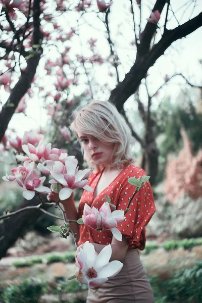 Mulher bonita em pé entre ramos sakura, menina bonita relaxante ao ar livre. Cores rosa suave — Fotografia de Stock