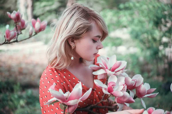 Mulher bonita em pé entre ramos sakura, menina bonita relaxante ao ar livre. Cores rosa suave — Fotografia de Stock