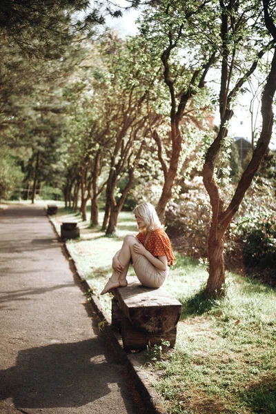 Hermosa mujer sentada en el banco cerca de los árboles, chica bonita relajándose al aire libre. Colores verdes suaves. Parque — Foto de Stock