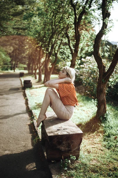 Mulher bonita sentada no banco perto das árvores, menina bonita relaxante ao ar livre. Cores verdes suaves. Parque — Fotografia de Stock