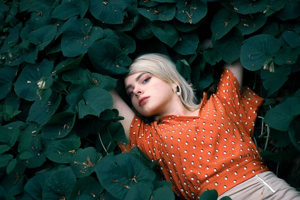 Mulher bonita deitada entre plantas verde-escuras, menina bonita relaxante ao ar livre. Close-up Imagens Royalty-Free