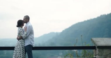 Dışarıda bekleyen sevgi dolu bir çift. Adam kadını alnından öper. Kadın başını omzuna koyar. Aşık insanlar ve güzel doğa.