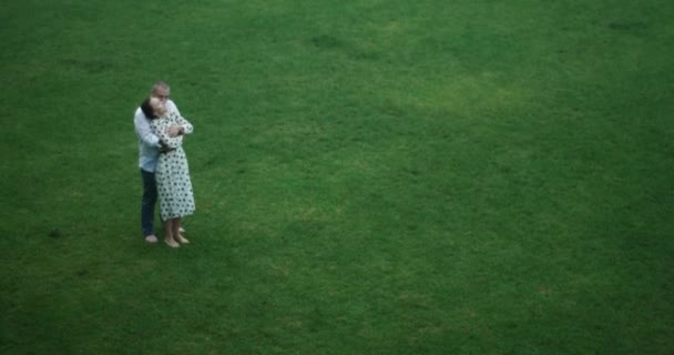 Любляча пара обіймає стоячи під дощем на яскраво-зеленому полі. красива природа. щасливі люблячі люди . — стокове відео