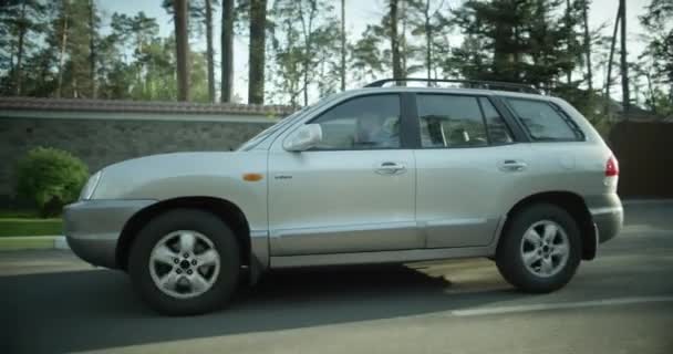 El coche va en una zona residencial de la ciudad. SUV gris. el coche monta en la vista lateral de la carretera . — Vídeos de Stock