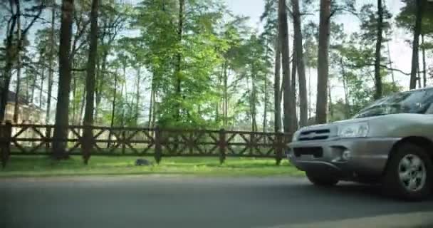 Šedé auto jede po silnici. na pozadí parku a stromů. — Stock video