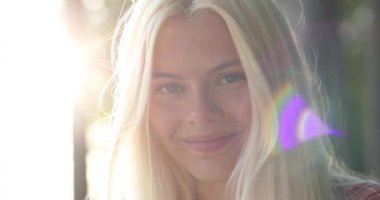 Büyüleyici, altın sarısı saçları, büyük kahverengi gözleri olan çekici genç bir bayan doğada ürperiyor. 4K video. Güneş patlamaları.