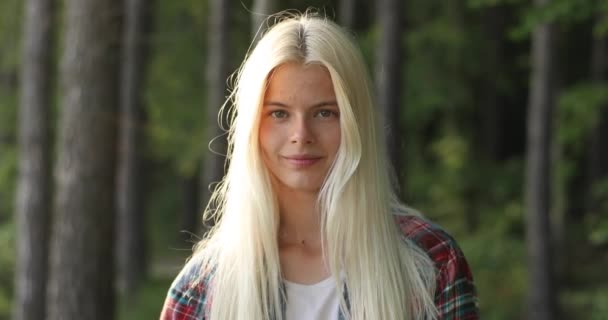 Encantador retrato de mujer joven. Con un magnífico cabello dorado, grandes ojos marrones, la atractiva jovencita se está relajando en la naturaleza, mirando a cámara. Acampar. Verano. Vídeo 4K. Viajes . — Vídeos de Stock