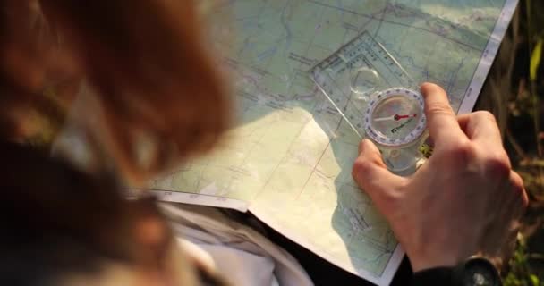 Chlápek s mapou přemýšlející o směru, kterým by se měl vydat, s kompasem na pravé ruce. Video 4K. — Stock video