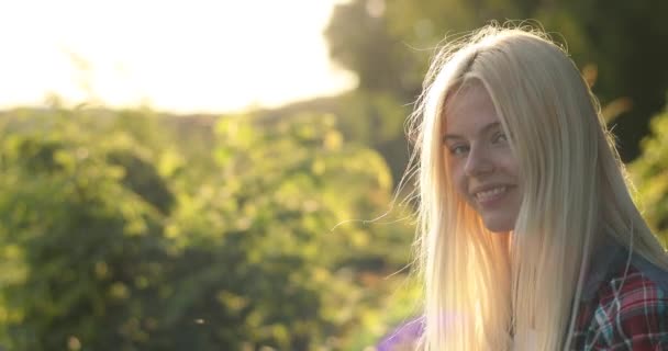 Γοητευτική νεαρή γυναίκα πορτρέτο. Με υπέροχα χρυσά μαλλιά, μεγάλα καστανά μάτια, η ελκυστική νεαρή κοπέλα κρυώνει στη φύση, κοιτάζοντας στην κάμερα. Κάμπινγκ. Σάμερ. Βίντεο 4K. Ταξίδι. — Αρχείο Βίντεο