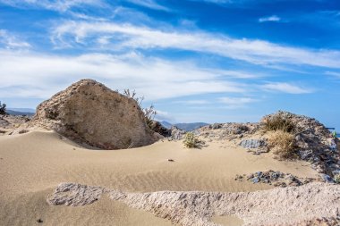 Kum tepeleri, taşlar ve mavi gökyüzü