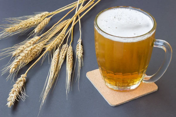 Taza de cerveza y trigo sobre fondo negro — Foto de Stock