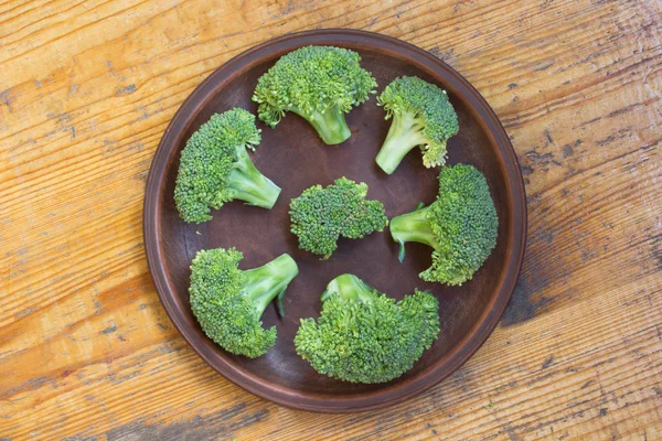 Broccoli på en brun tallrik på trä bakgrund. ovanifrån — Stockfoto