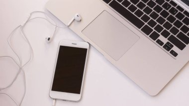 Dizüstü bilgisayar ve telefon masada kulaklıklarla. Yakın çekim. Üstten görünüm