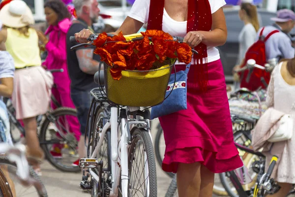 Uma mulher de saia vermelha segura o guidão de uma bicicleta . — Fotografia de Stock